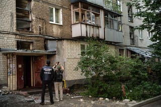 A man takes photographs of a damaged residential building following Russian drone strikes in Kharkiv